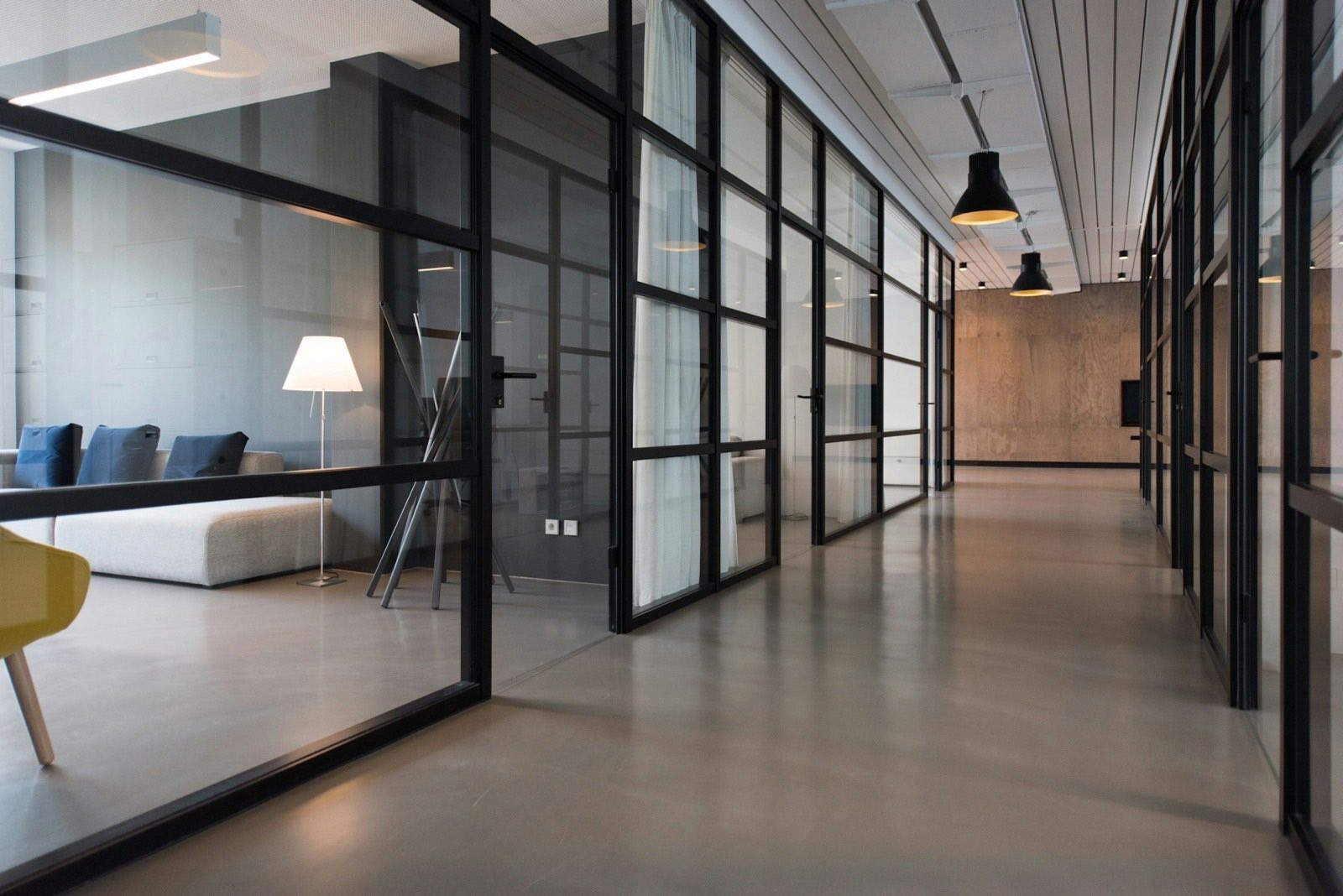Modern office corridor with glass-partitioned meeting rooms